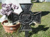 Iron Southern Cross of Honor beside a pot of flowers on a grave
