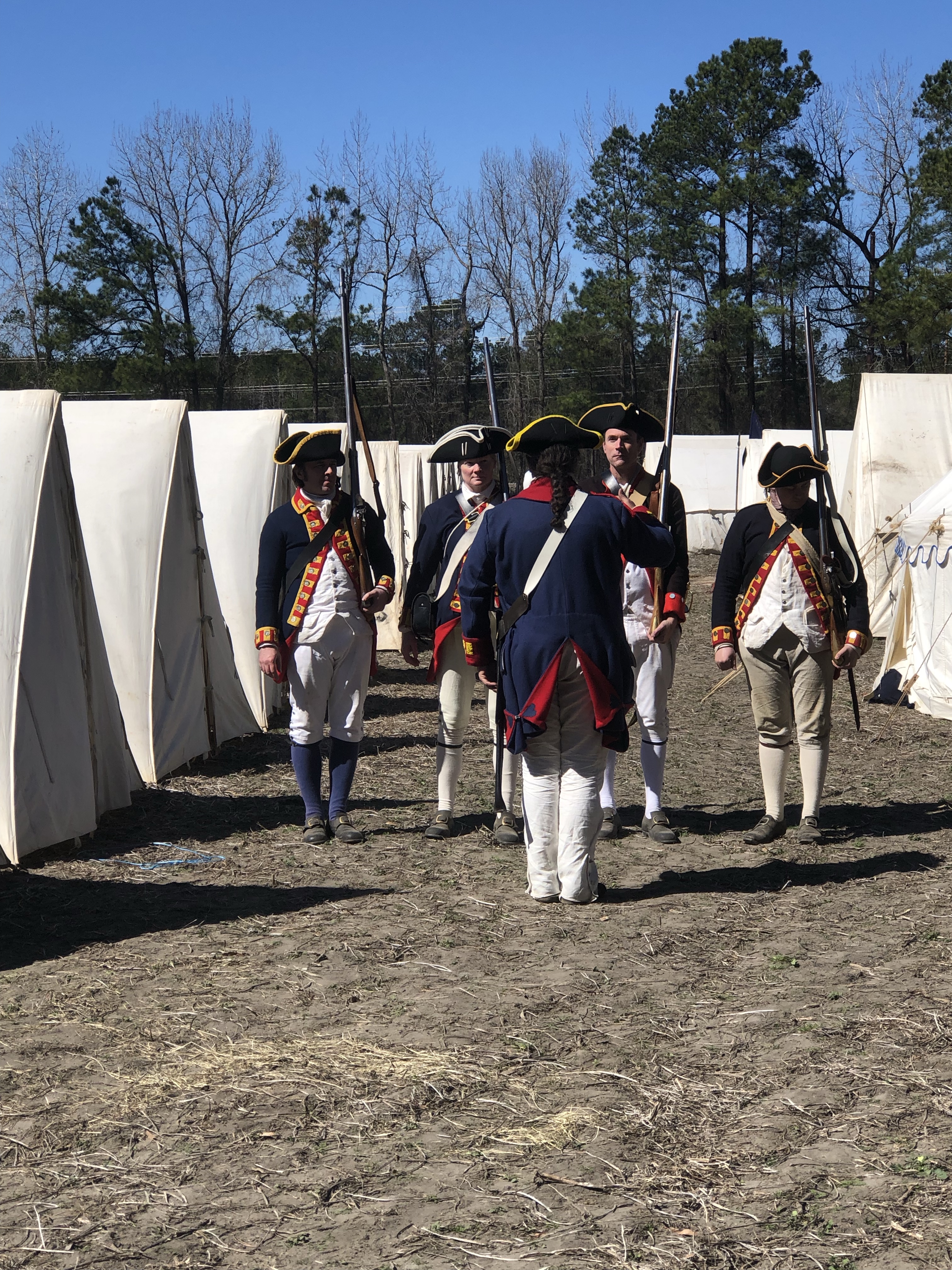 Reenactors in Continental Army uniforms standing in the camp