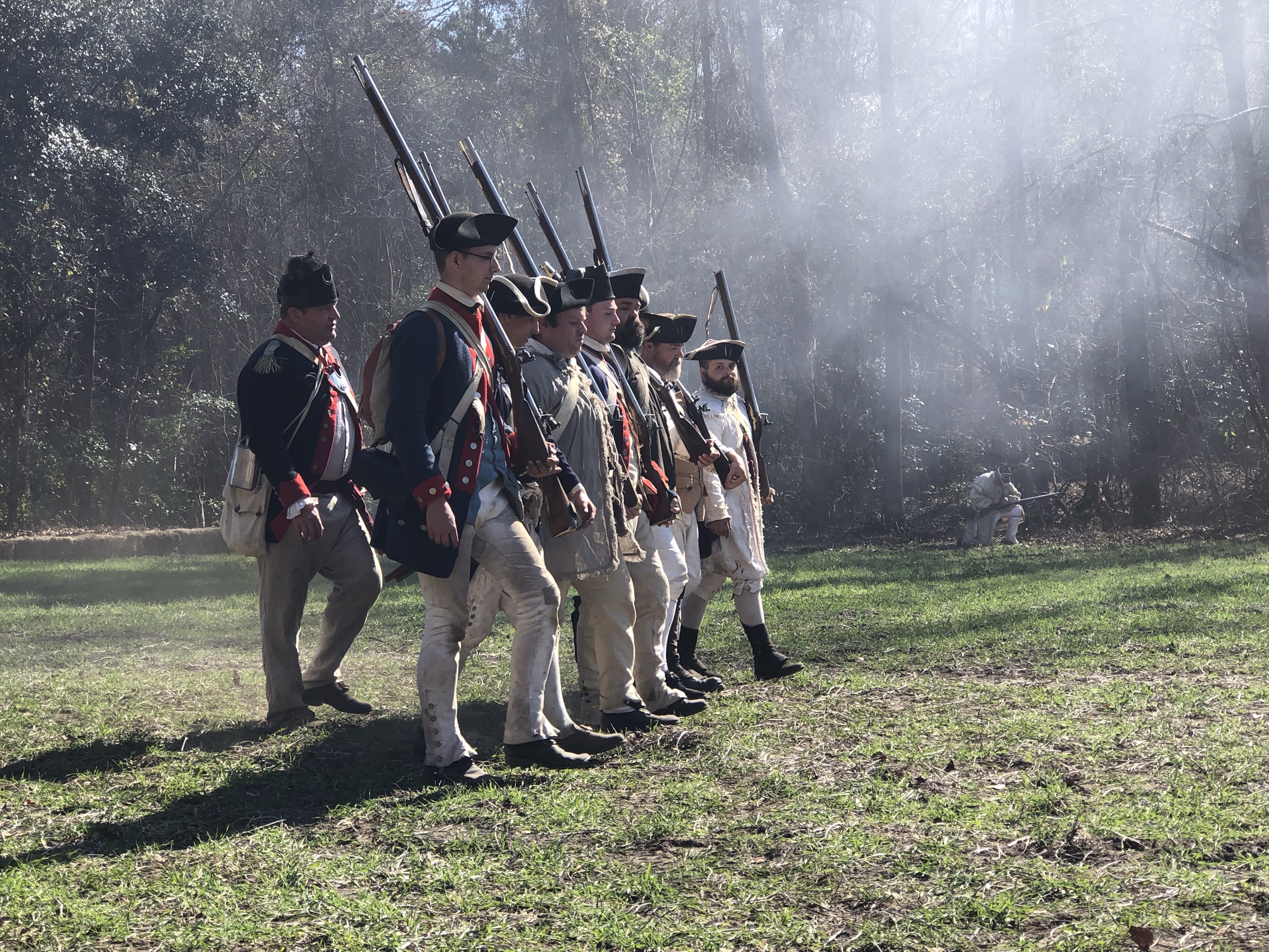 Reenactors marching with muskets through battle smoke