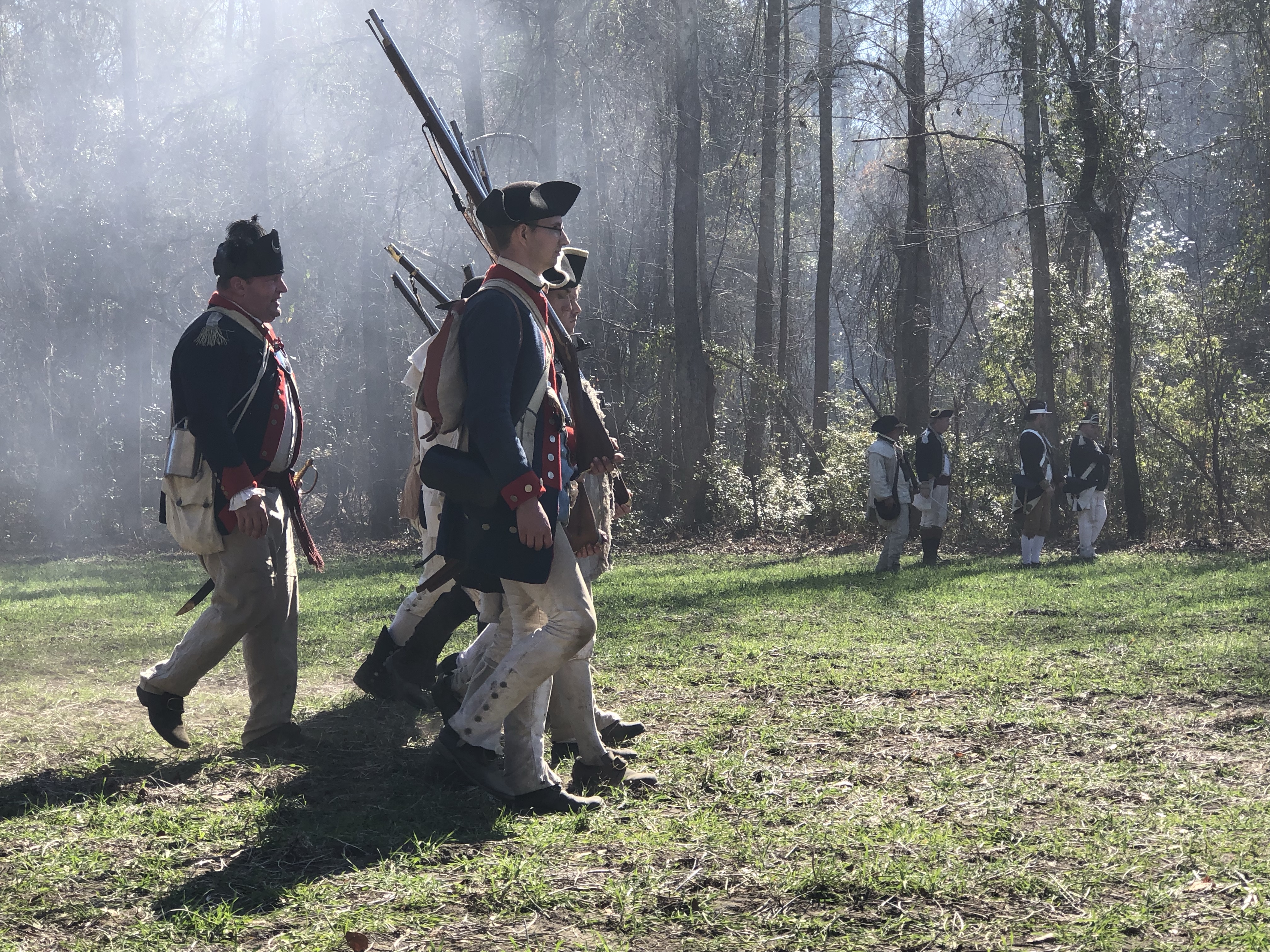 Column of reenactors with shouldered muskets in the smoke