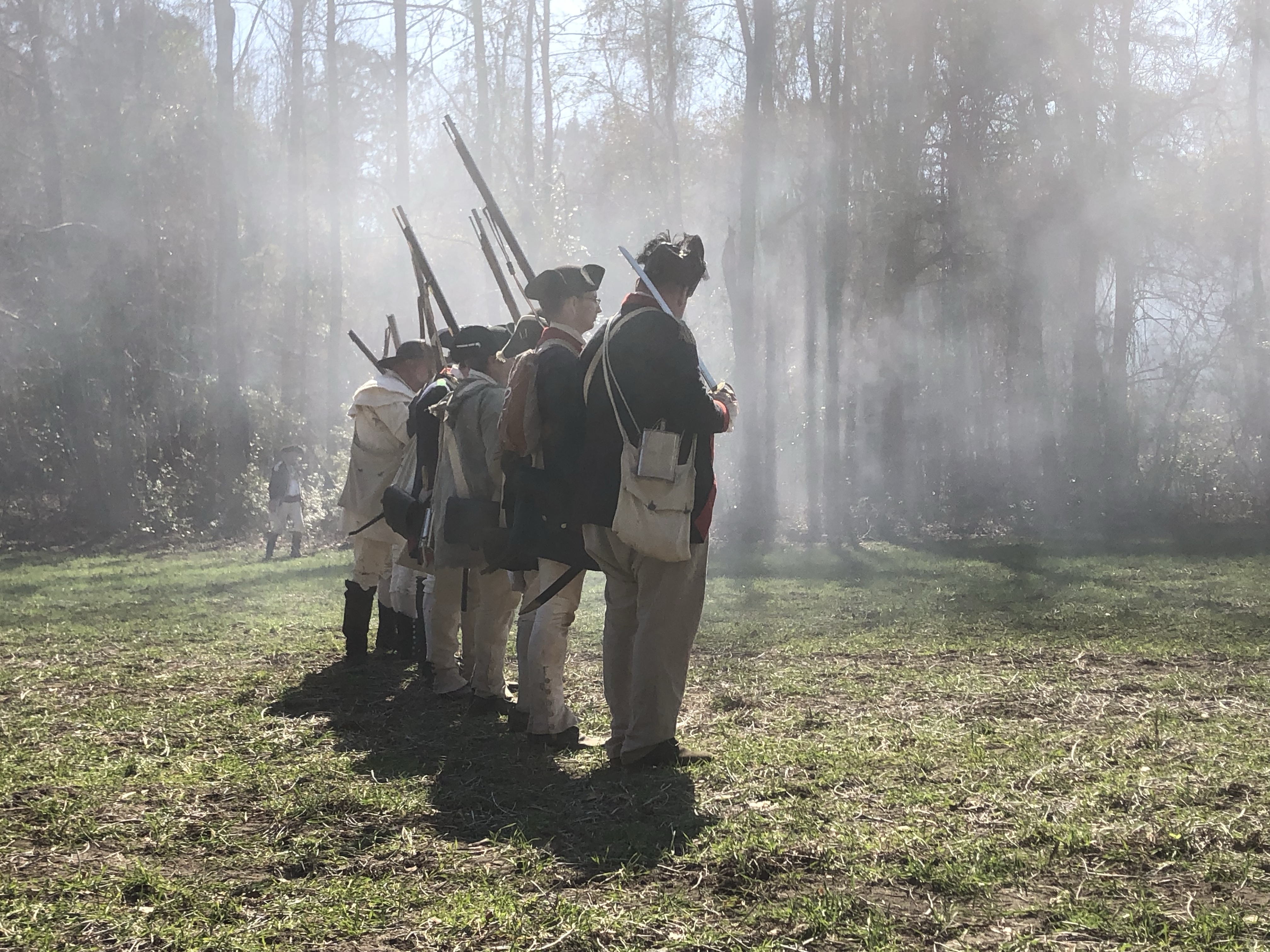 Reenactors standing in the hazy sunlit smoke
