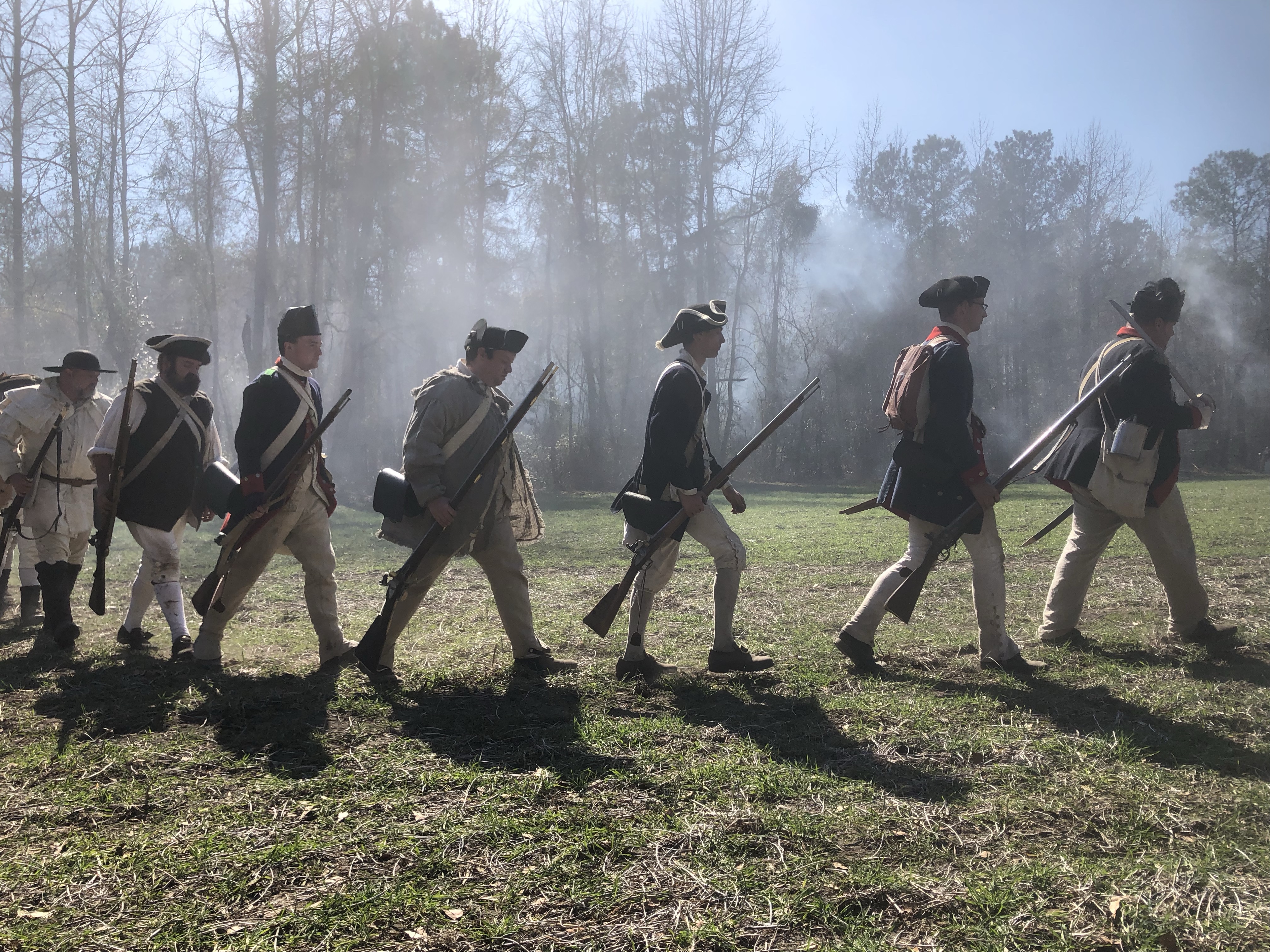 Line of militia reenactors advancing across the field