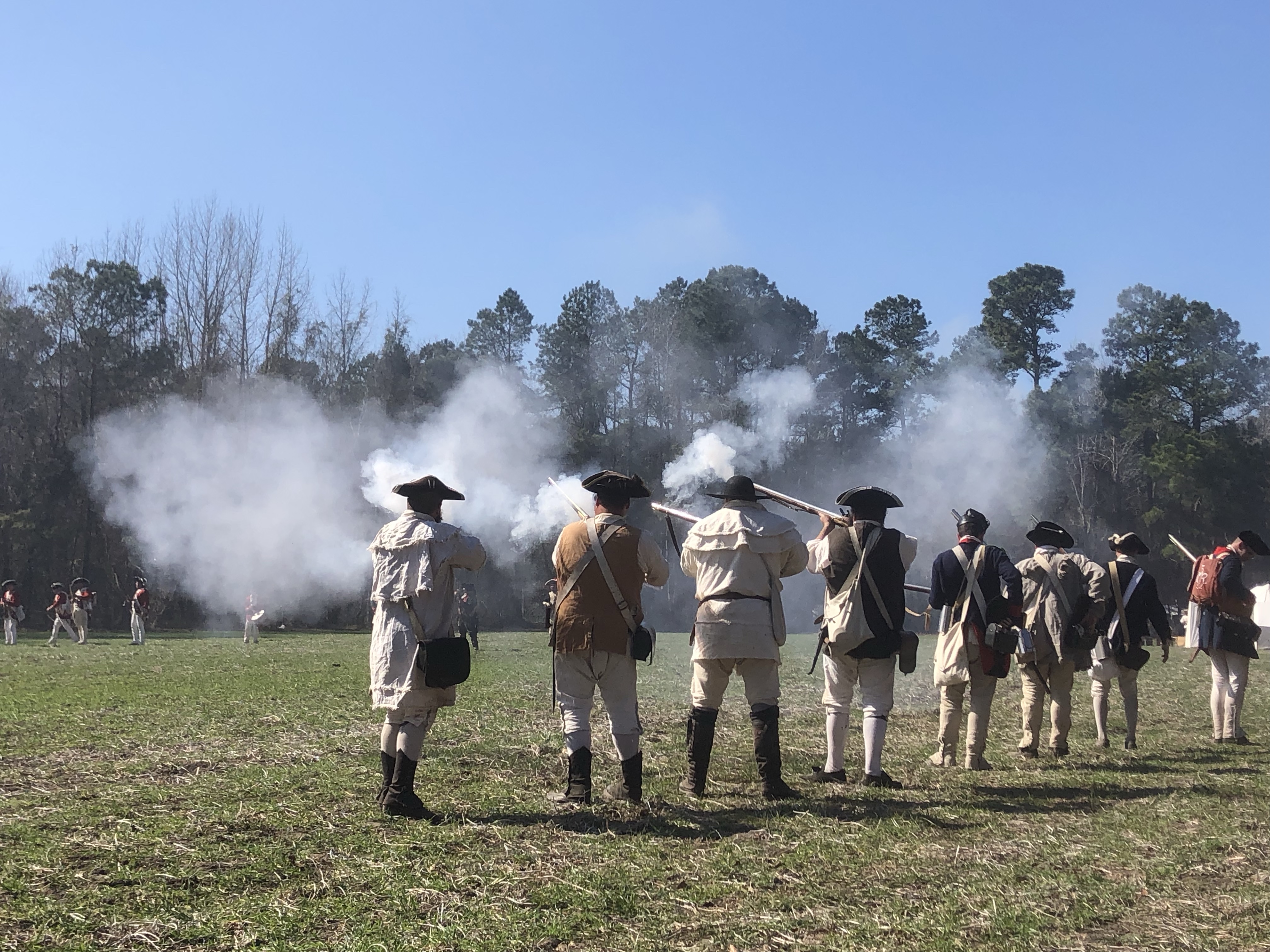 Musket smoke rising over a line of reenactors