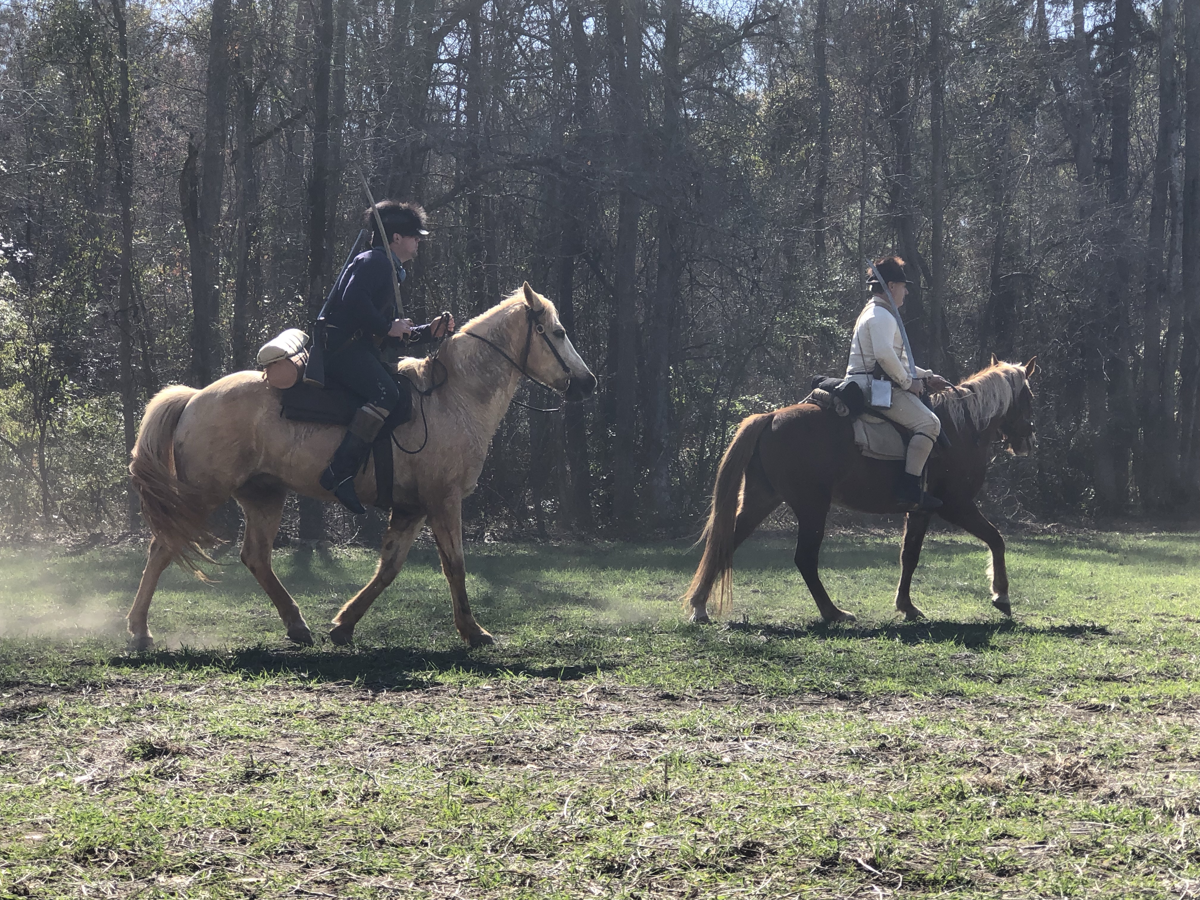 Two reenactors on horseback crossing the field