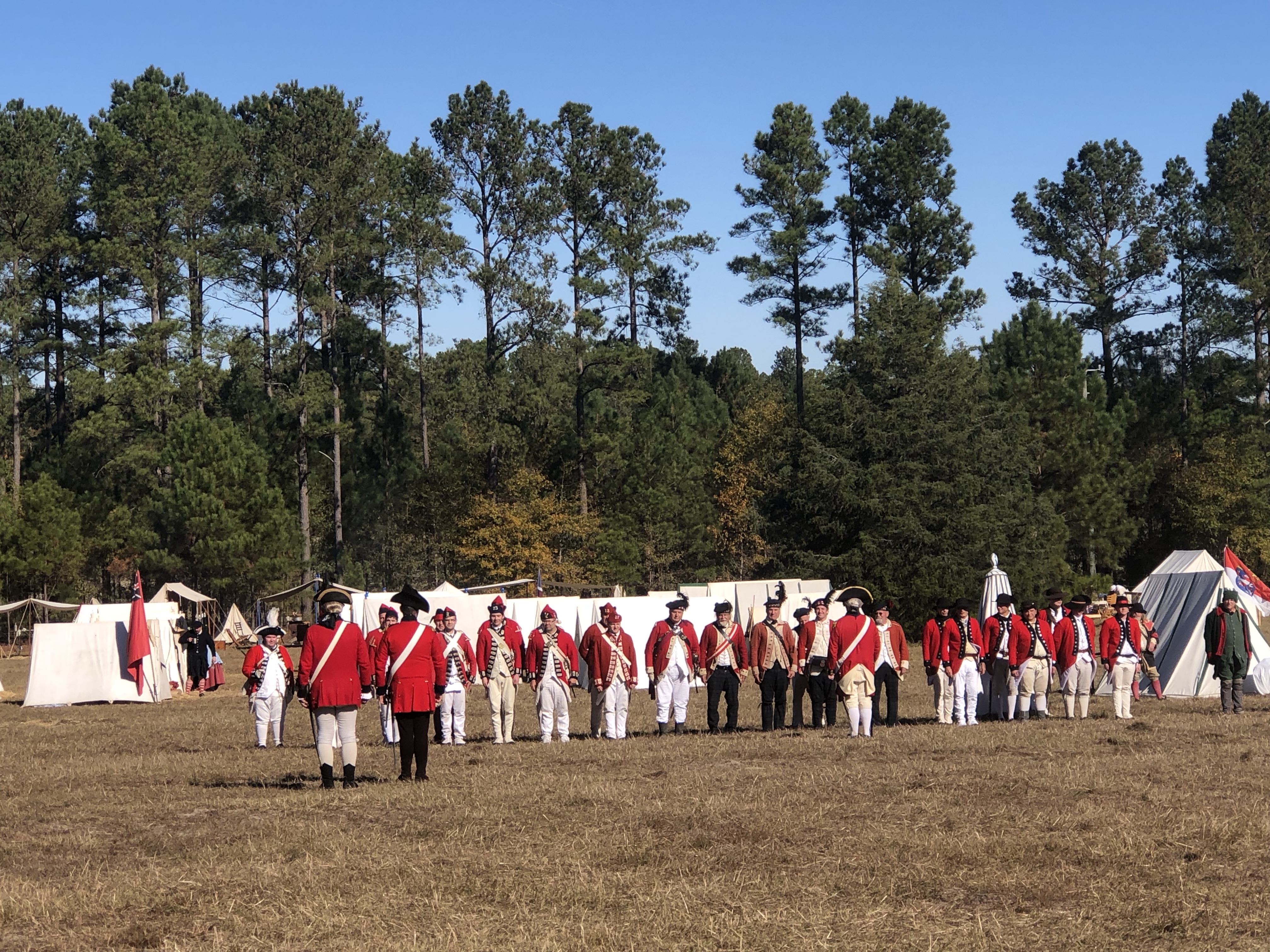 Reenactors in red coats lined up before white tents at the American Heritage Festival