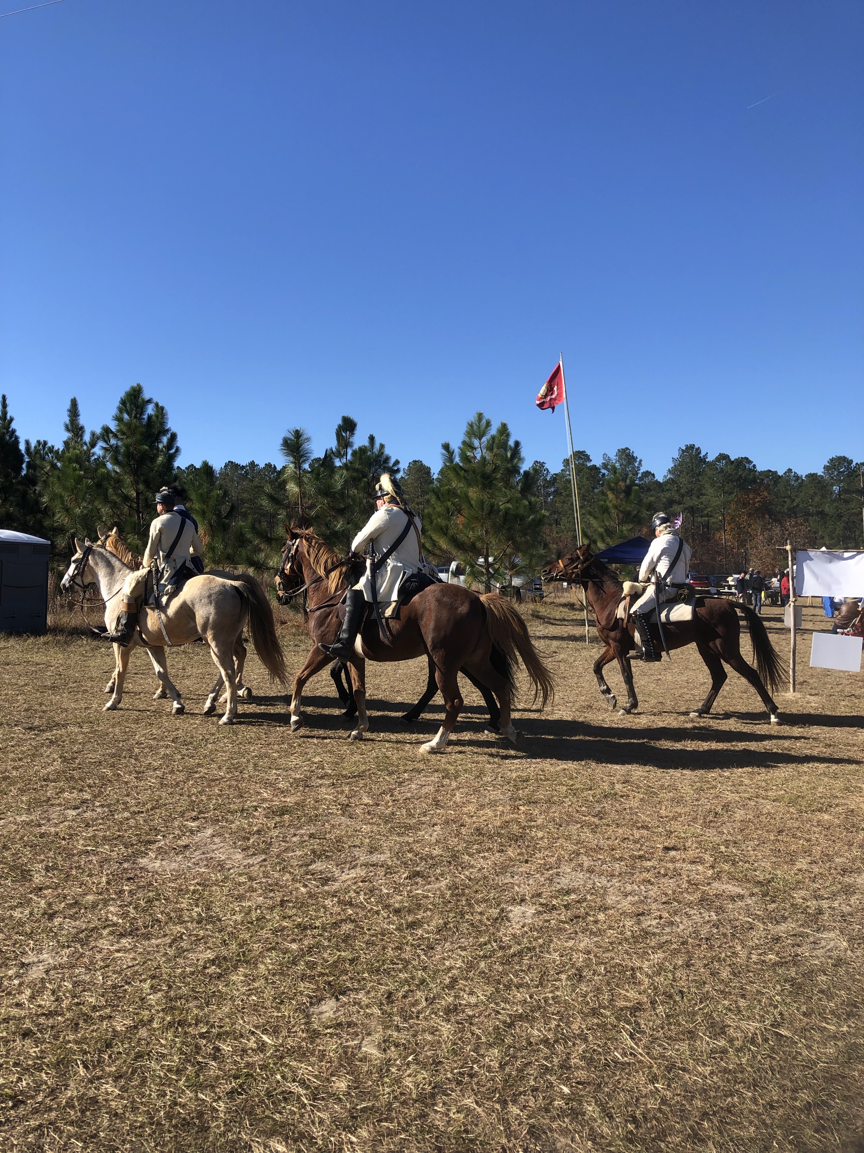 Cavalry reenactors on horseback with a red flag at the reenactment