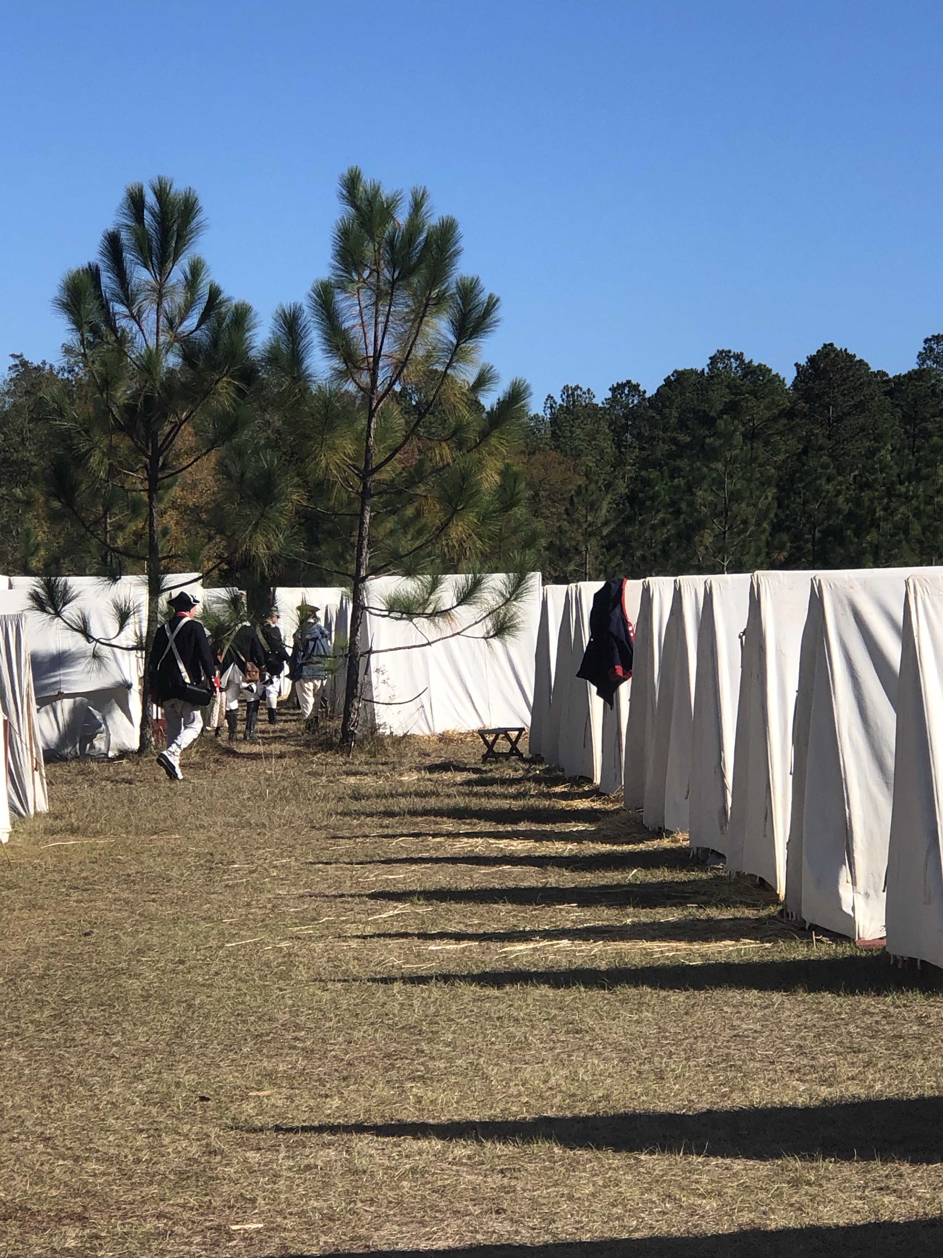 Shadowed lane between rows of white tents in the reenactment camp