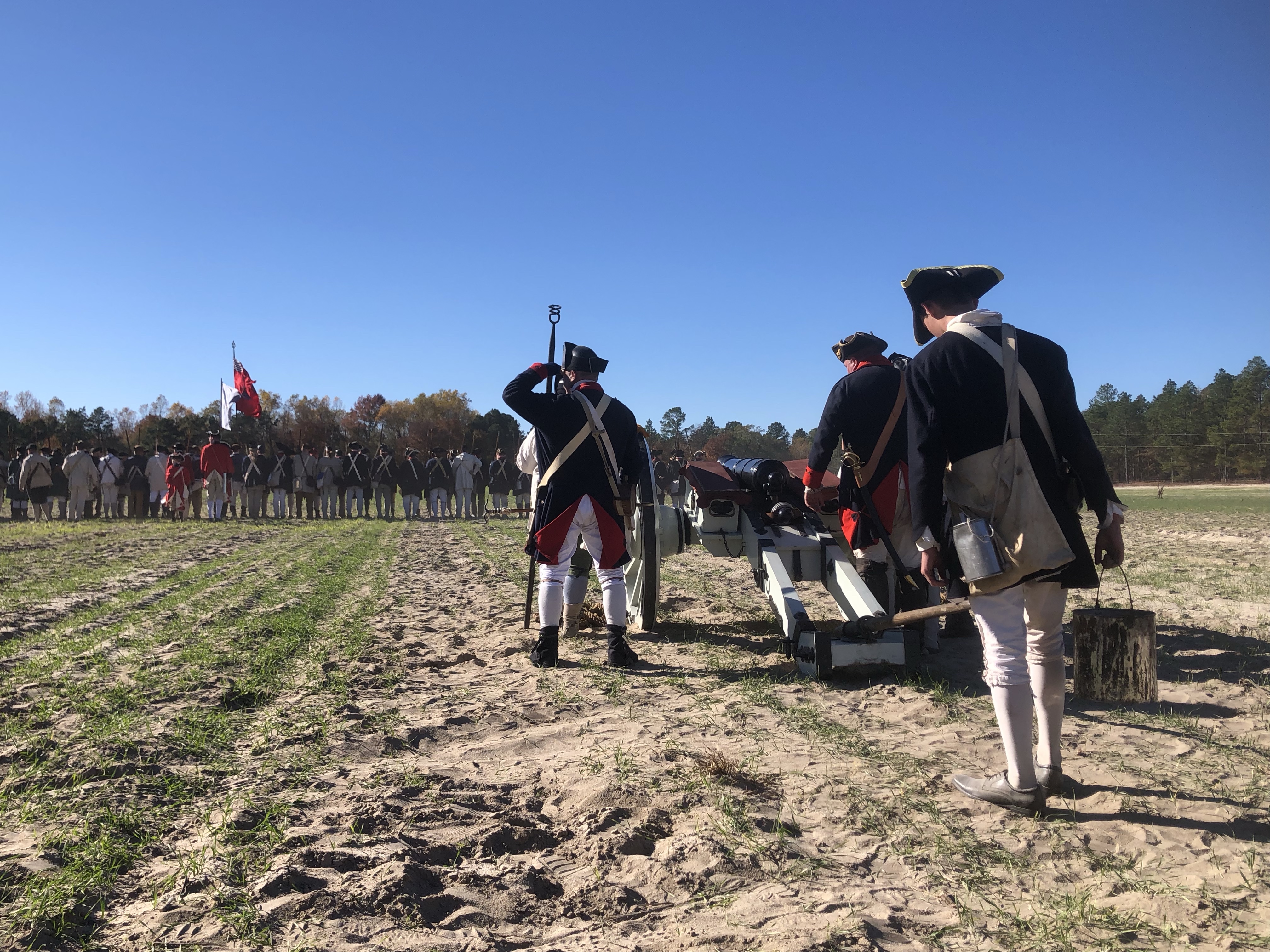 Artillery crew in tricorn hats at their gun with the battle line behind