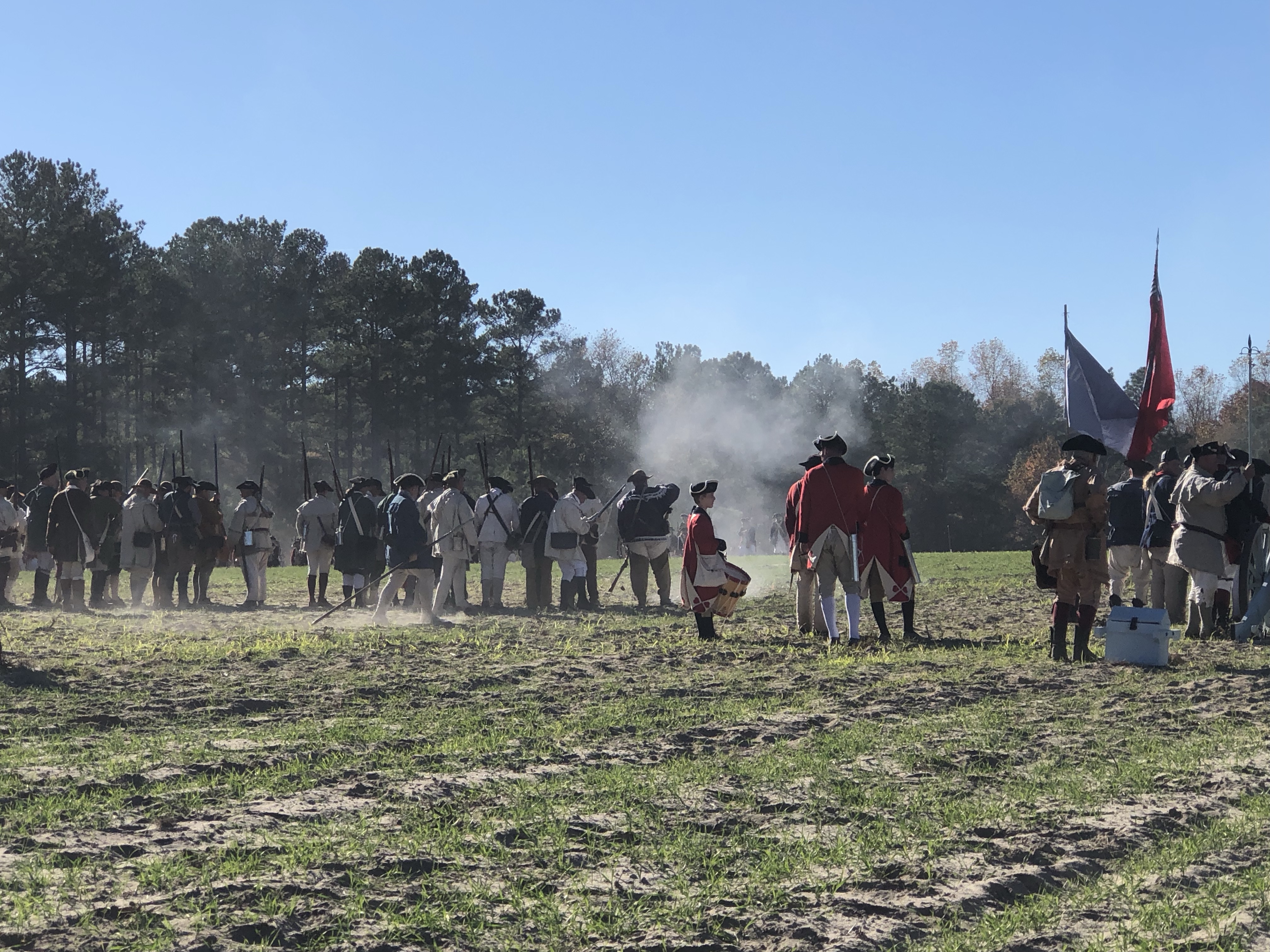 Opposing lines of reenactors with flags and smoke on the field