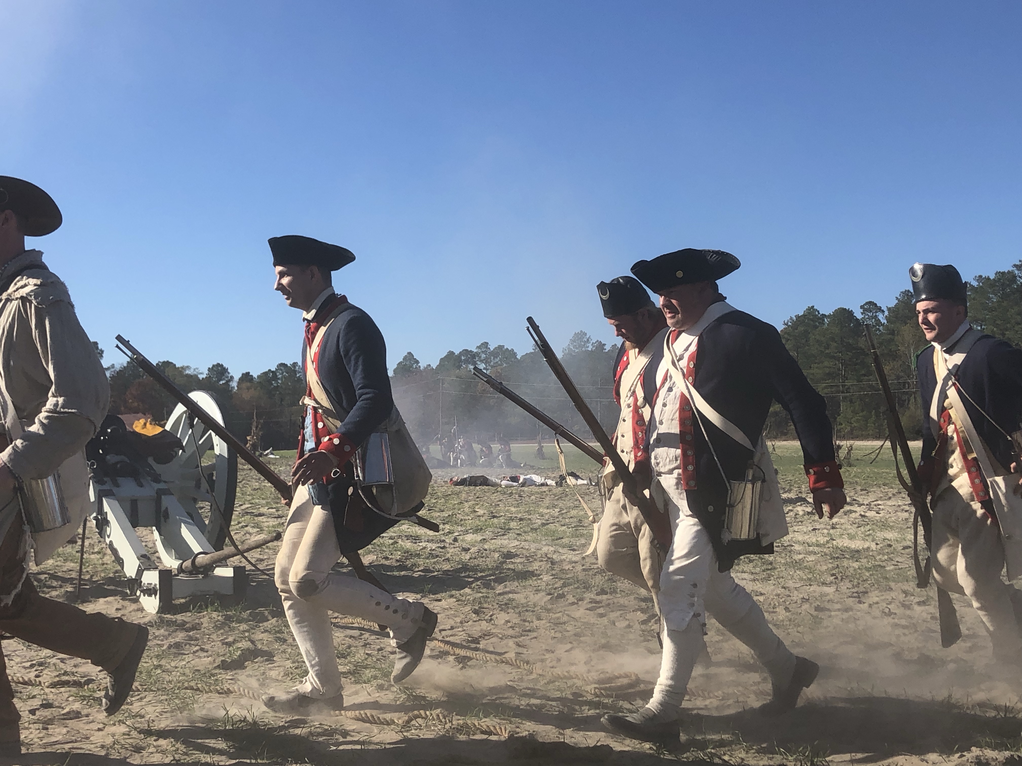 Militia reenactors running across the field with muskets