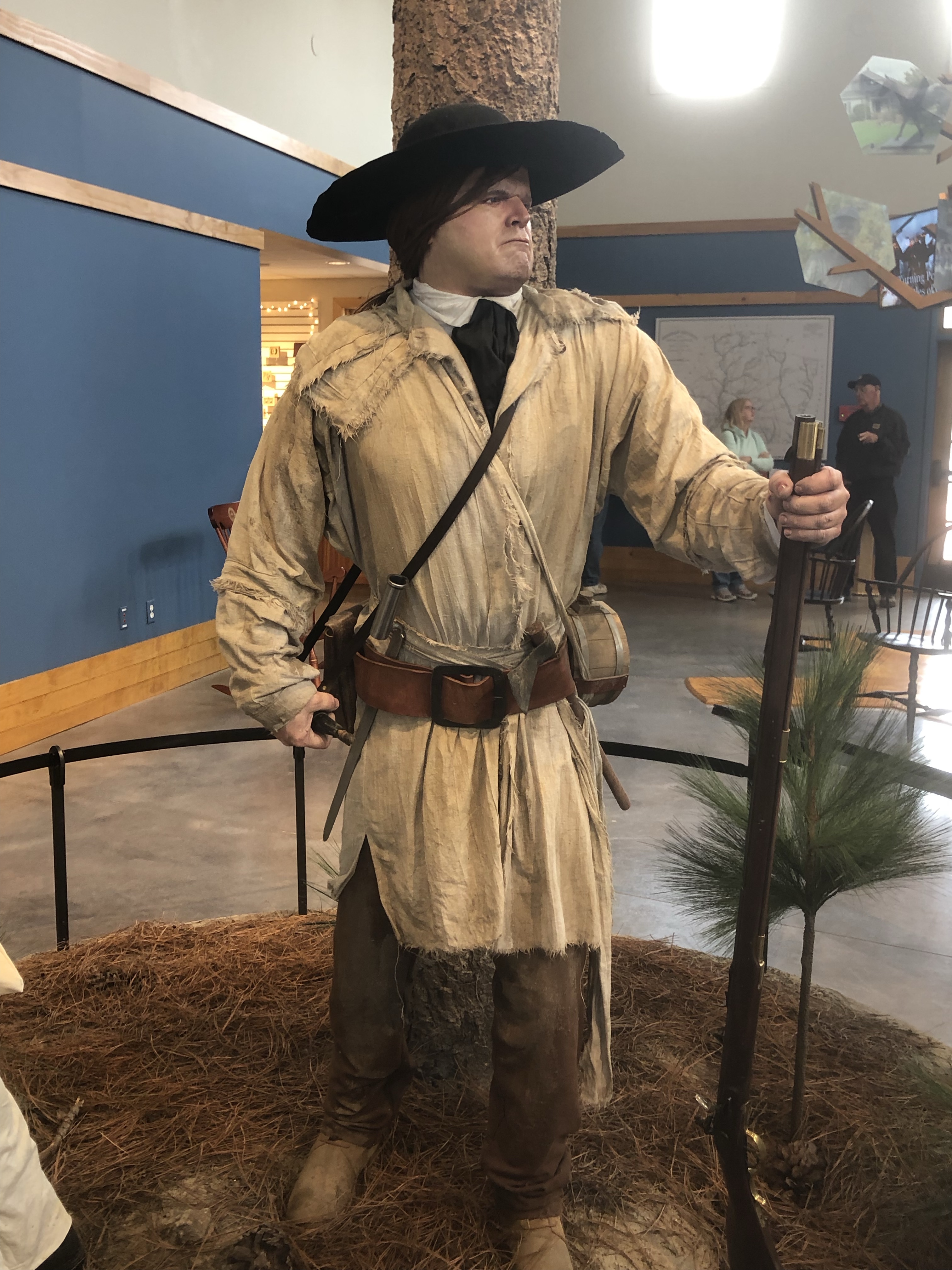 Life-size figure of a backcountry militiaman in a hunting shirt and wide-brimmed hat holding a rifle