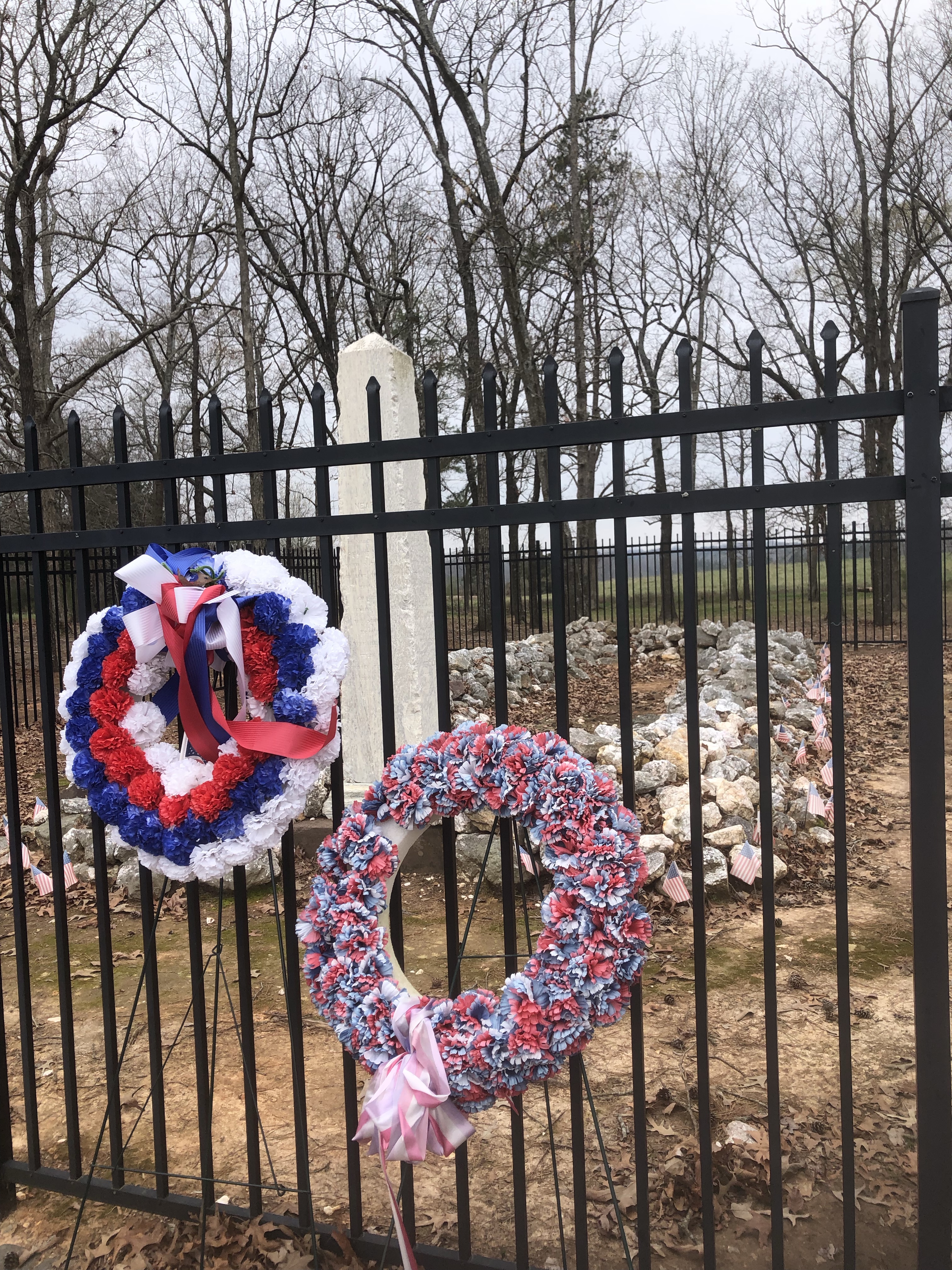 Red, white and blue wreaths on the iron fence around the mass grave at the Waxhaws battlefield