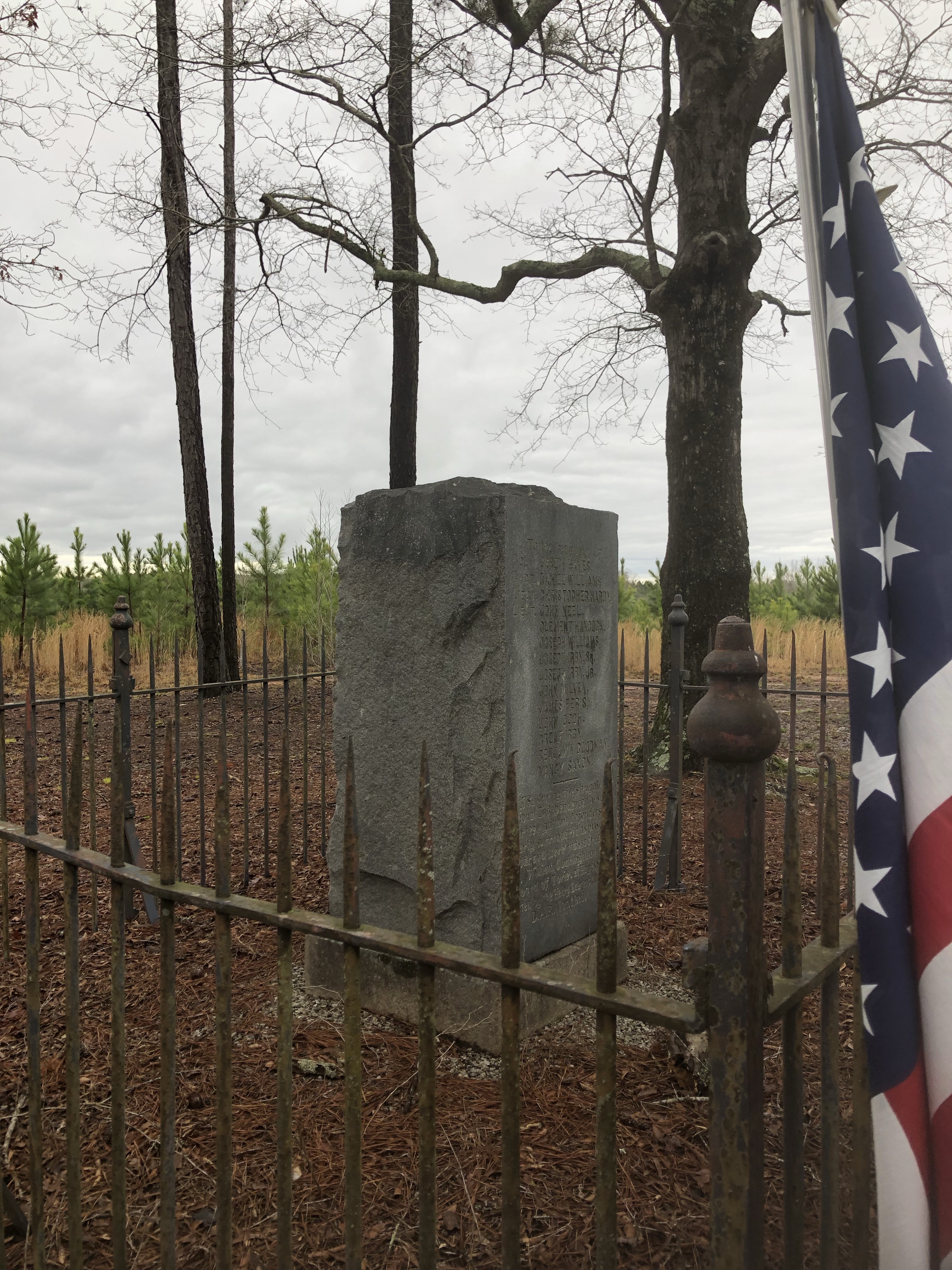 The Hayes Station monument inside its iron fence with an American flag beside it, March 2022