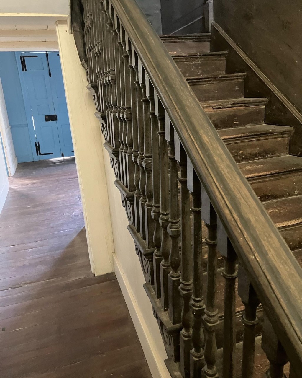 Wooden staircase with turned balusters beside a blue door