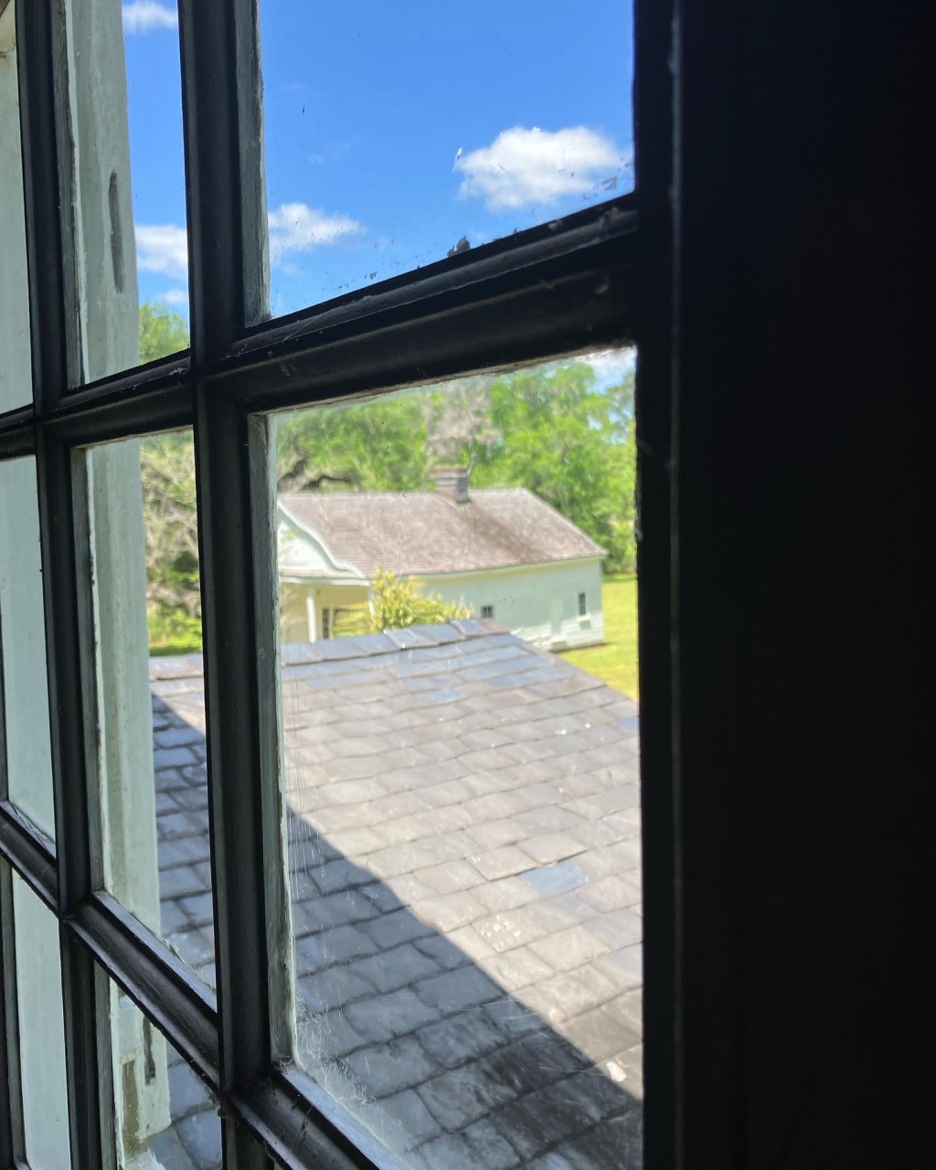 Upstairs window looking down on a roof and outbuildings