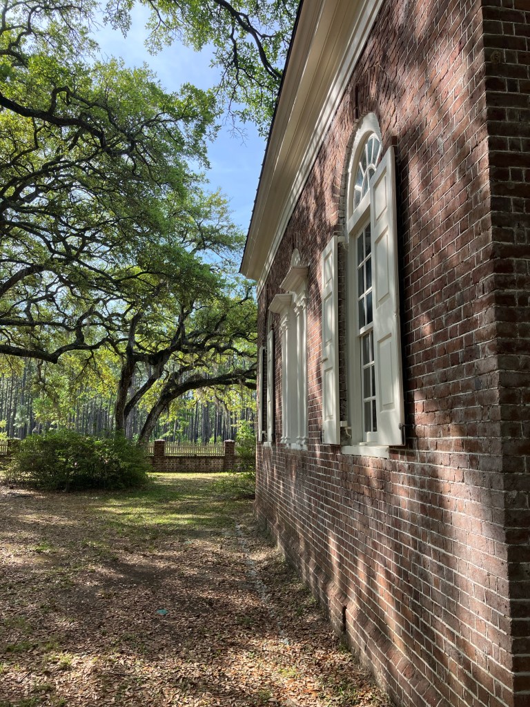Brick side wall and windows with live oaks
