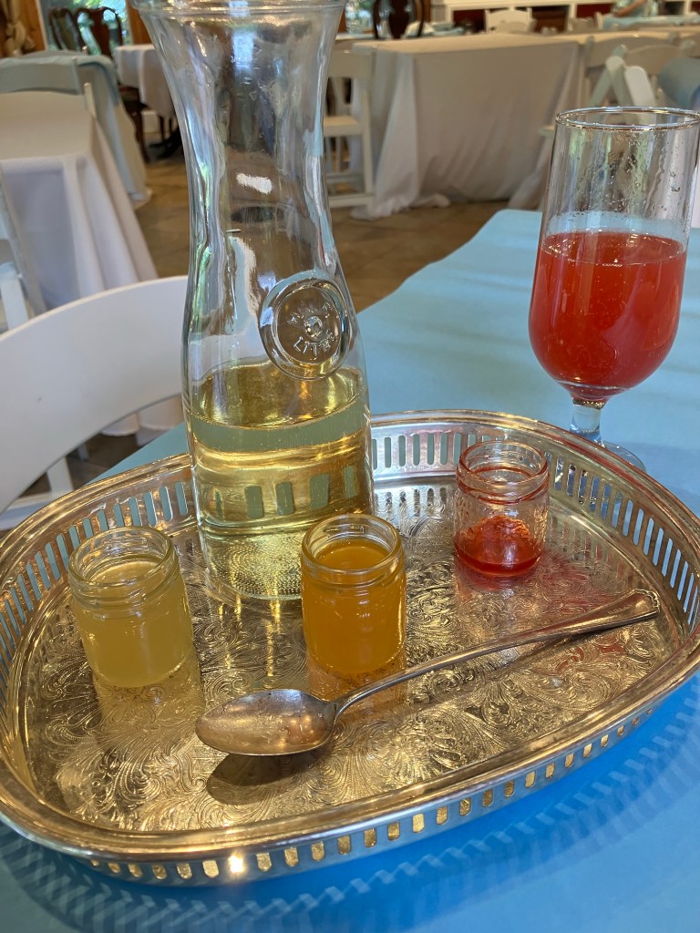 Silver tray with a carafe, small jars and a glass of red champagne punch in the tearoom