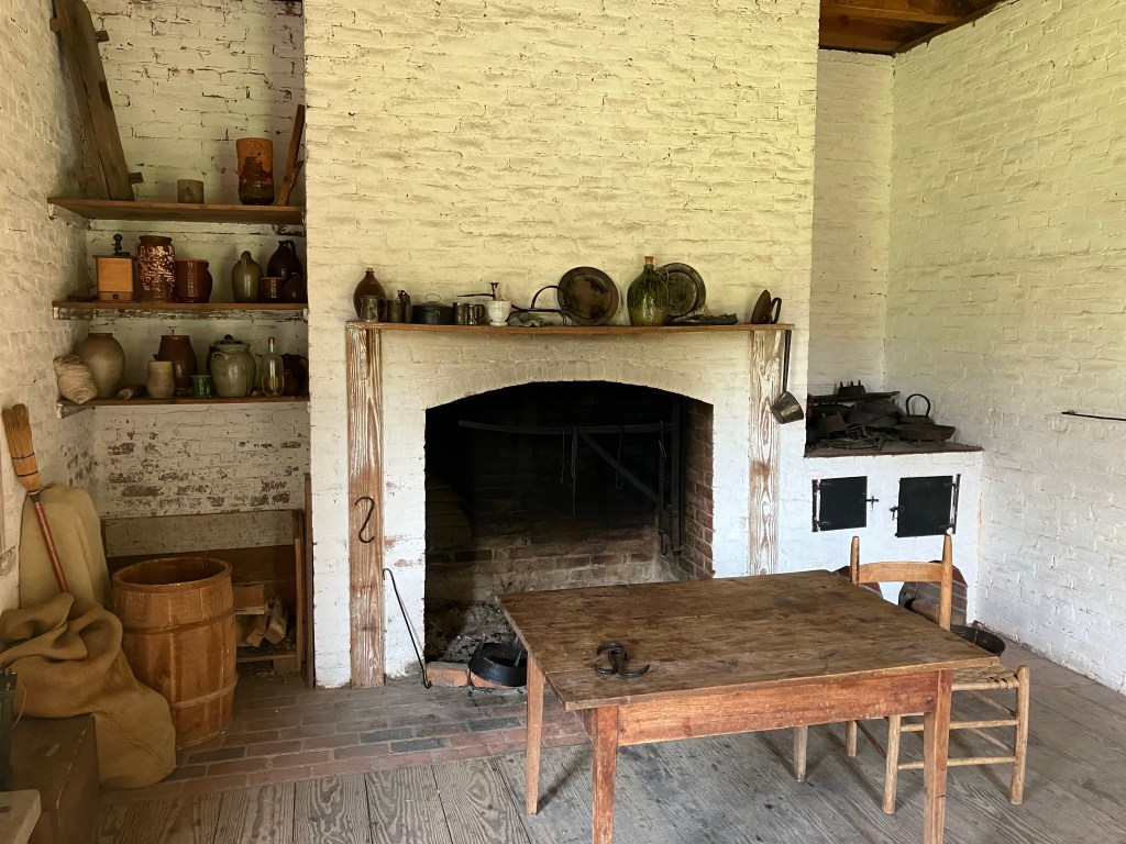 Restored kitchen with a hearth, table and cookware at Historic Brattonsville