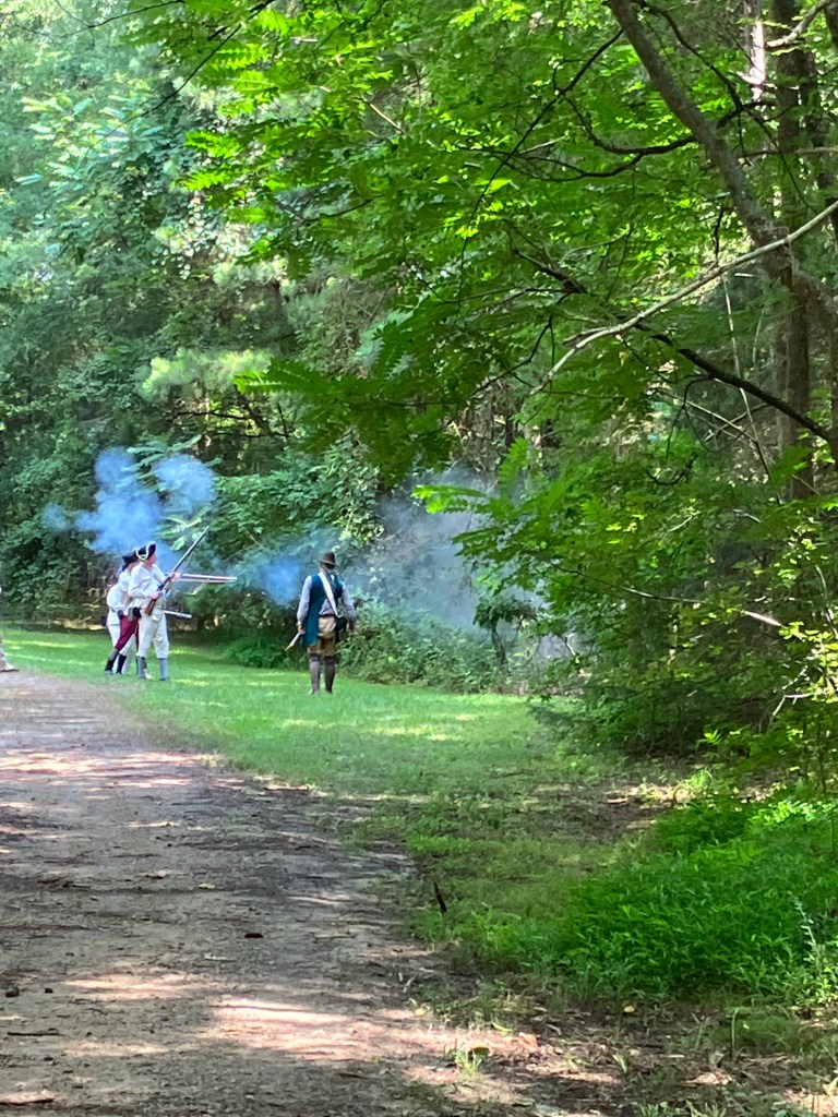 Reenactors advancing along a shaded dirt road at Historic Brattonsville