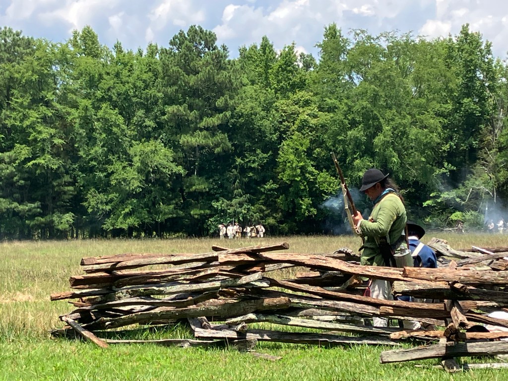 Reenactor militiamen firing from behind a rail fence at Huck's Defeat