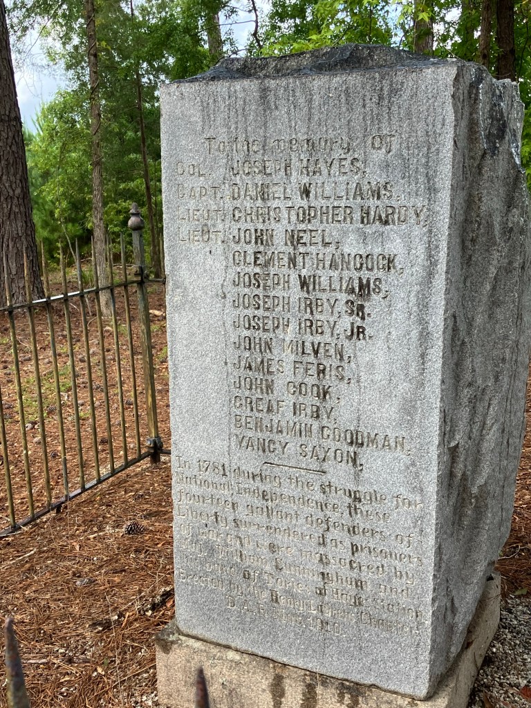 The 1910 granite Hayes Station monument listing the names of the men killed, inside its iron fence