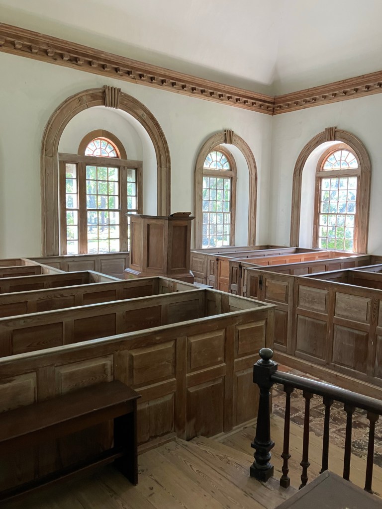Box pews and arched windows inside St. James Santee Church