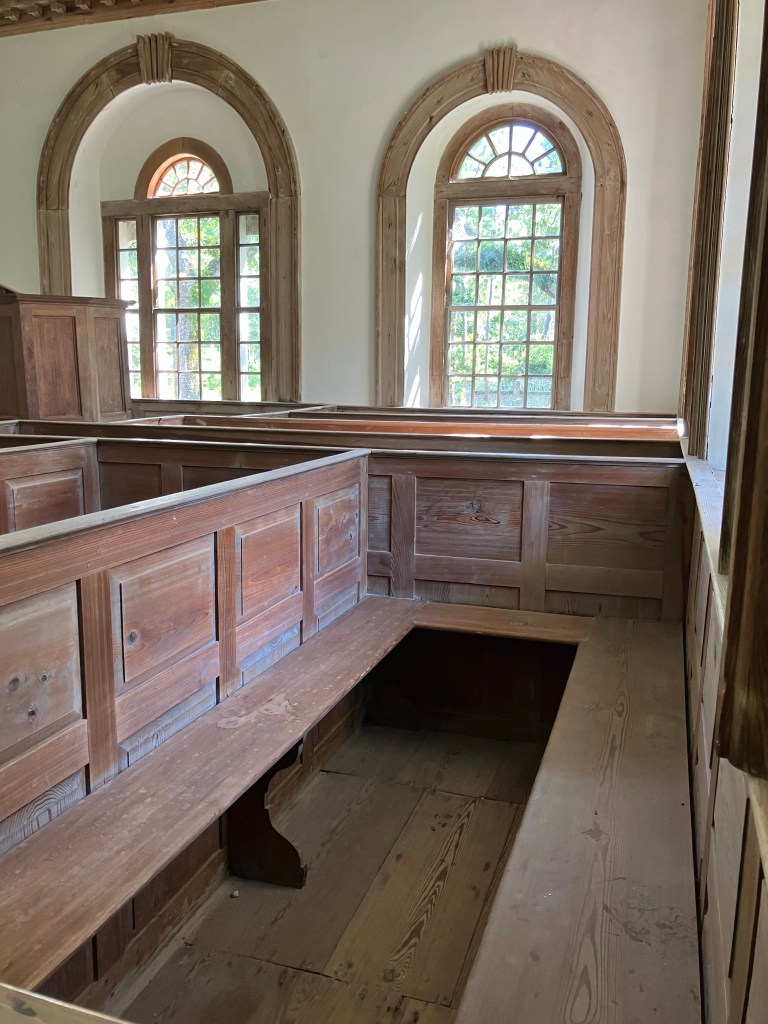 Box pews below two arched windows