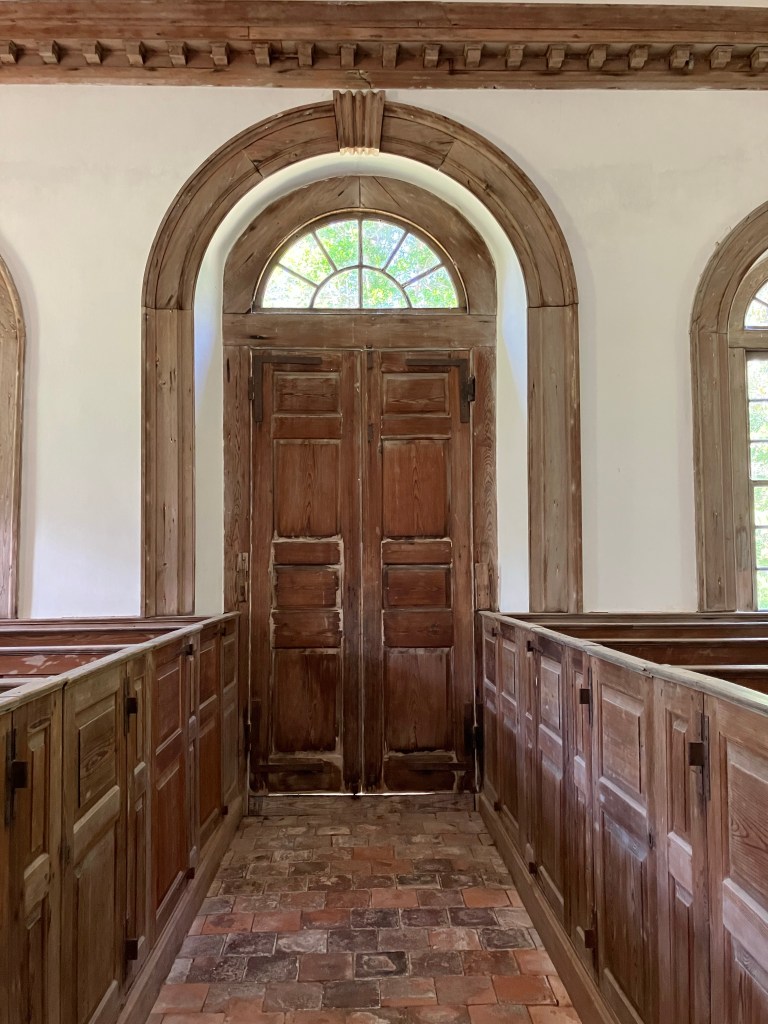 Arched paneled doors and box pews inside St. James Santee Church