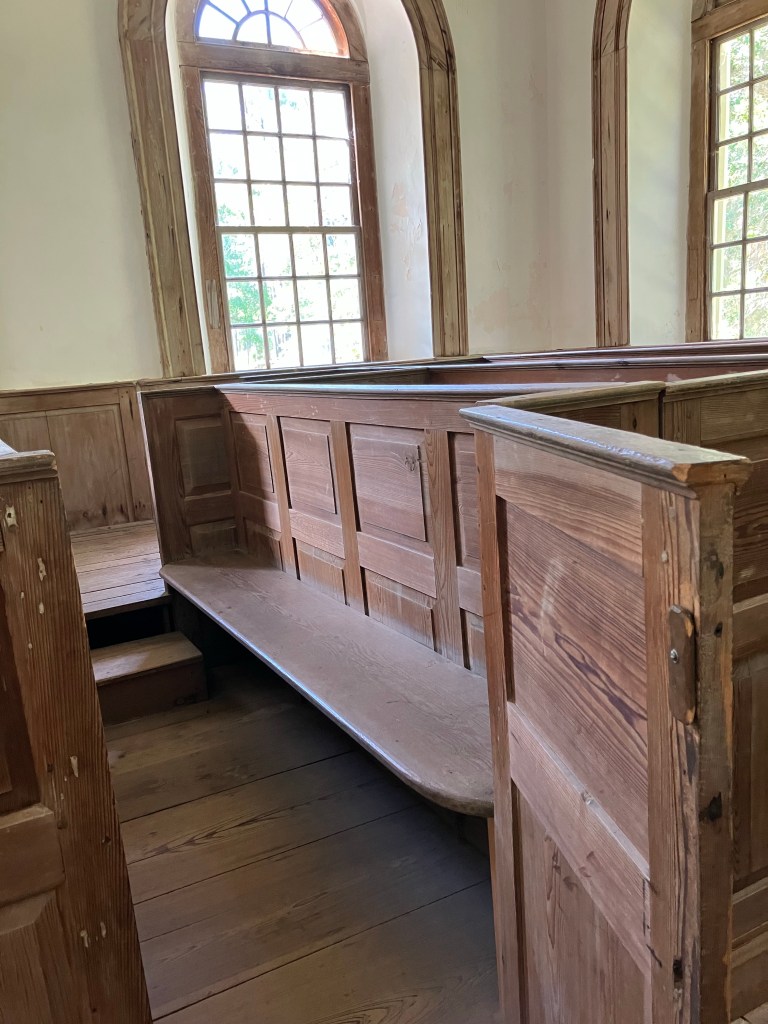 Bench inside a box pew below a tall window