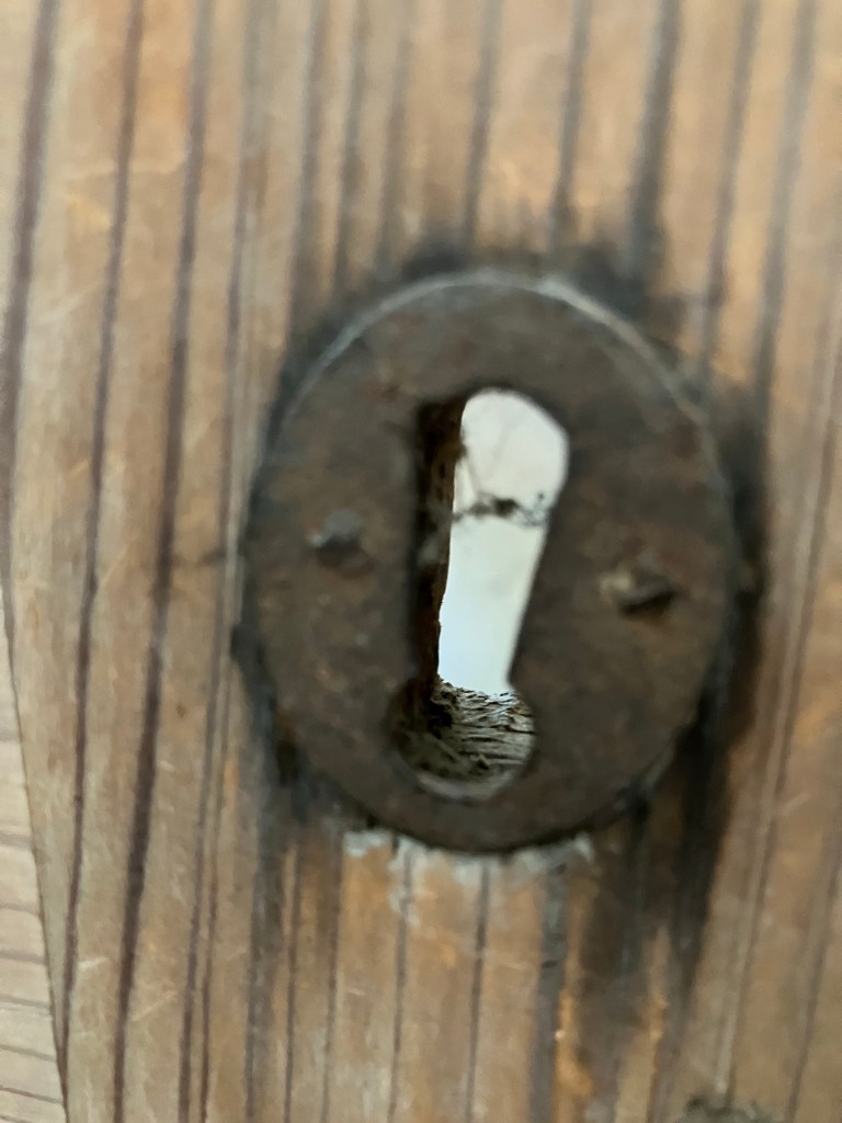 Close view of an old iron keyhole in the wood