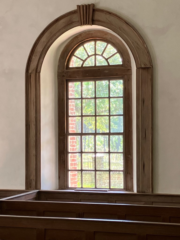 Arched window above the box pews