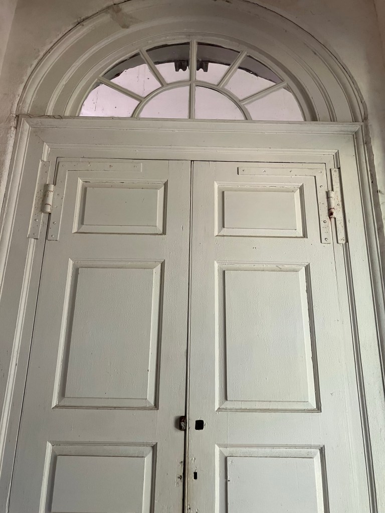 Tall white double doors under a fanlight