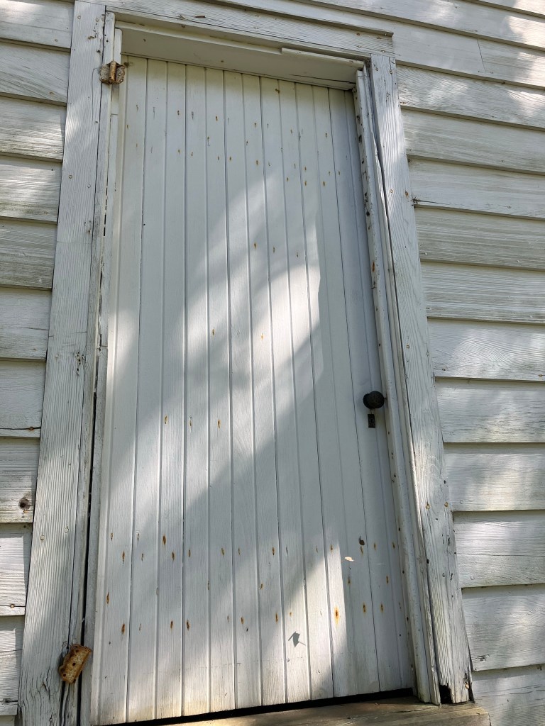 Weathered white door in a clapboard wall at Hampton Plantation