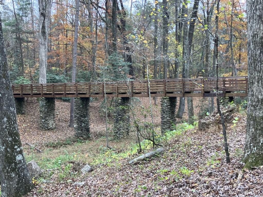 Long wooden footbridge on stone piers crossing a hollow