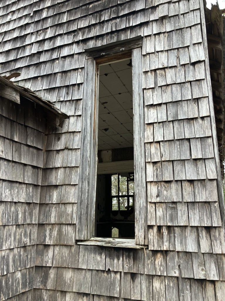 Empty window opening in the shingled wall of Halfway Creek Church