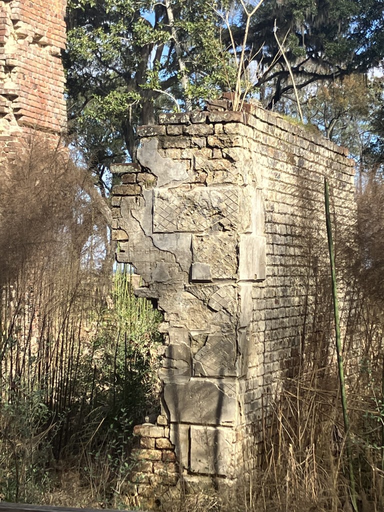 Stuccoed brick wall section standing in tall grass
