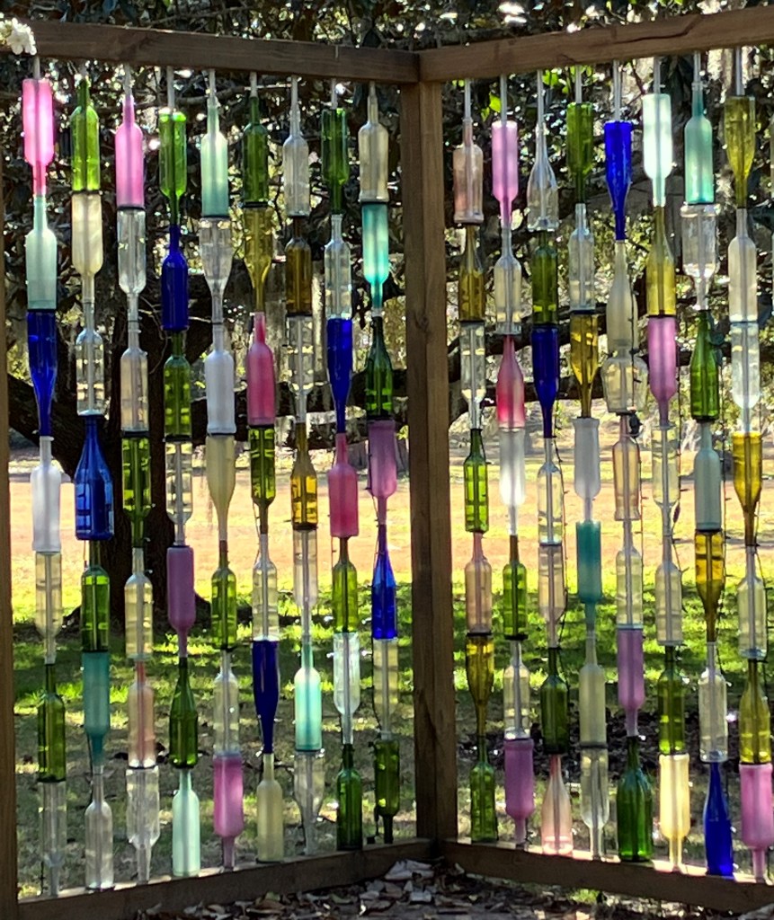 Wall of colored glass bottles hung on a frame like a bottle tree