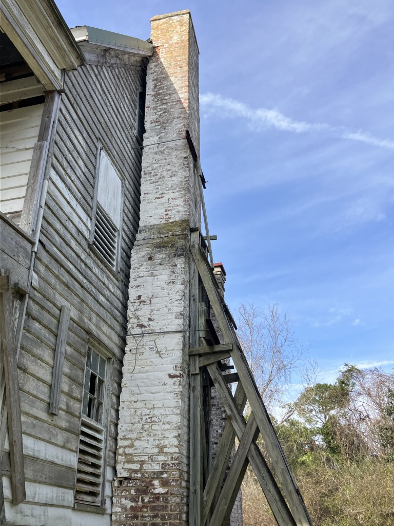 Tall brick chimney against the weathered siding of the Tibwin house