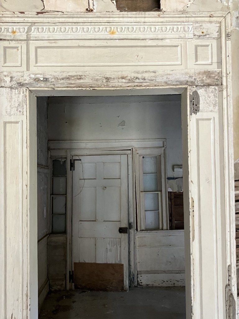 View through a tall carved doorway to another door