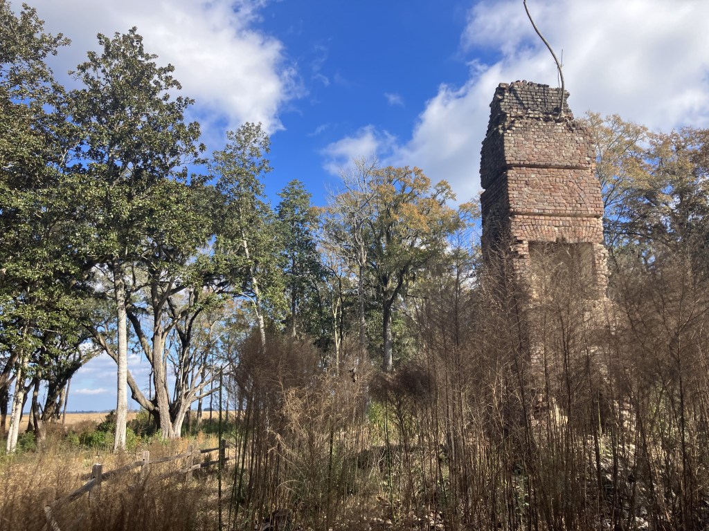 Distant brick chimney beyond the field and trees