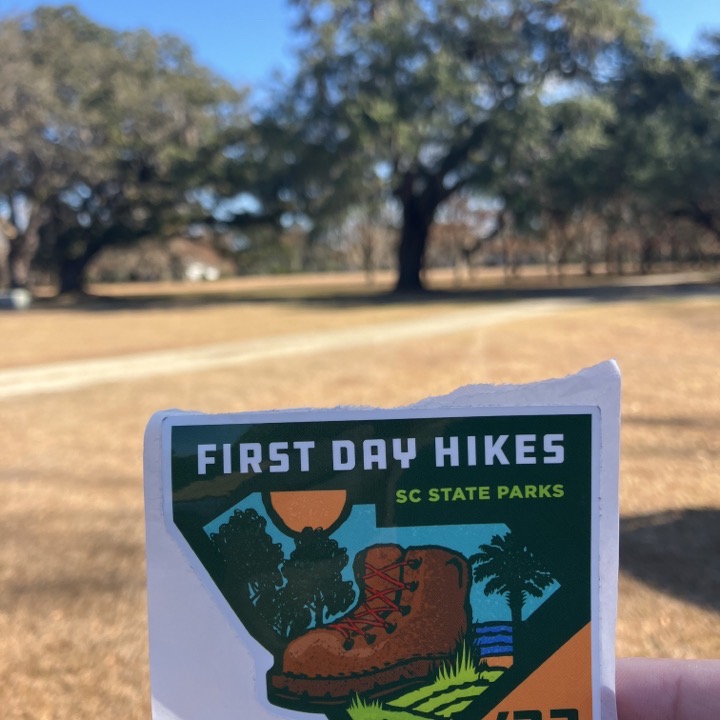 SC State Parks First Day Hikes sticker held up in front of the live oaks
