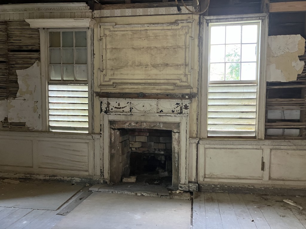 Room with a fireplace between two shuttered windows