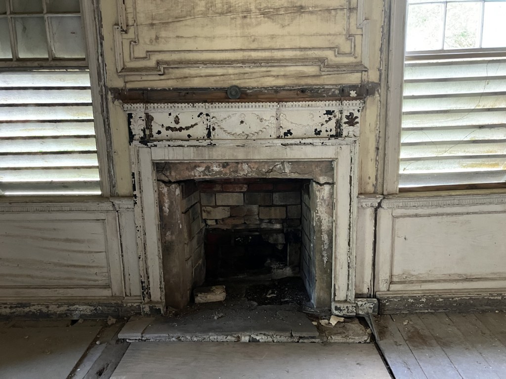 Carved wooden mantel and fireplace between shuttered windows