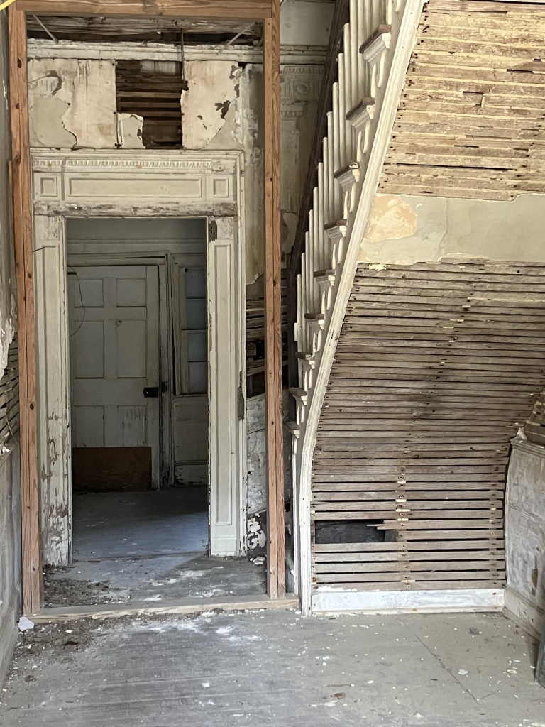 Center hall with a staircase and exposed lath under the stairs