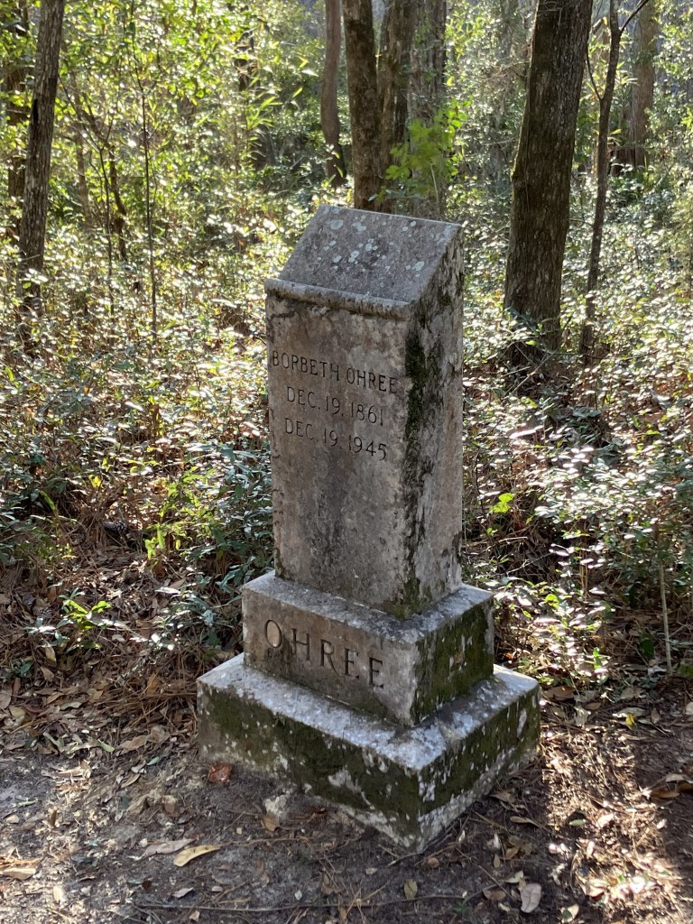Old stone grave marker on a base among the trees