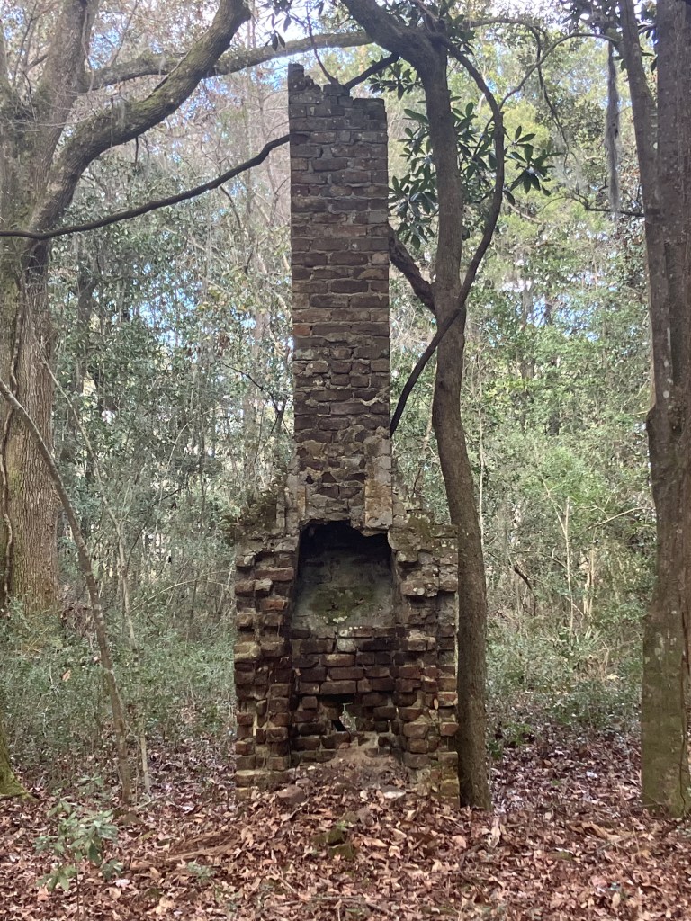 Tall brick chimney standing alone among the trees