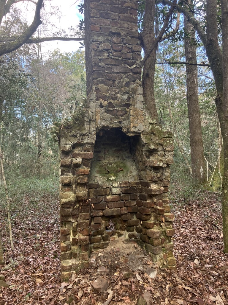 Crumbling brick cabin chimney standing in the woods