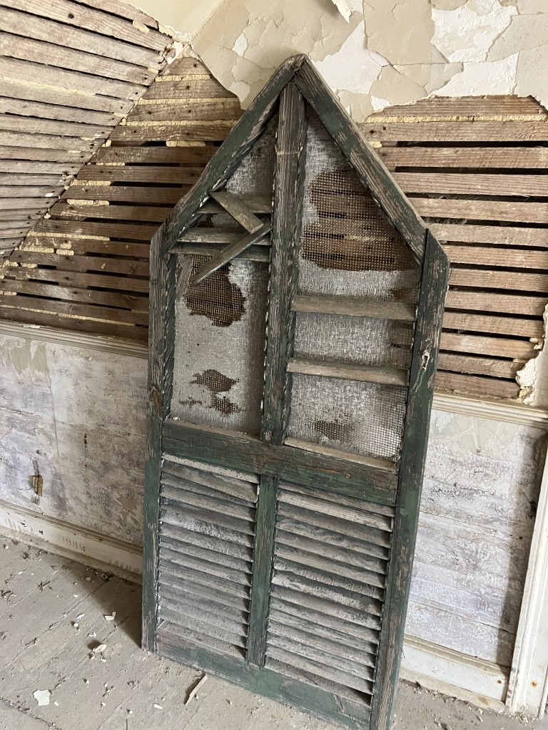 Pointed wooden shutter leaning against a lath wall
