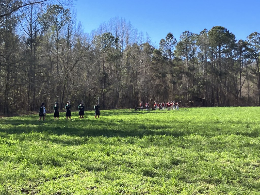 Small line of reenactors crossing the open field