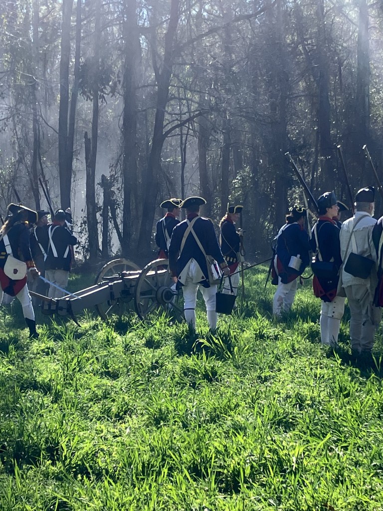 Reenactors in Continental uniforms gathered around a field gun